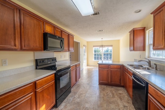 kitchen with visible vents, brown cabinets, a peninsula, black appliances, and a sink