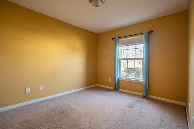 spare room featuring carpet flooring and baseboards