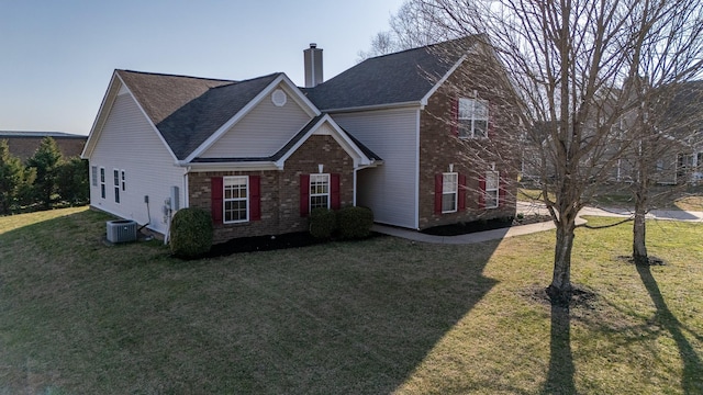 traditional home featuring cooling unit, roof with shingles, a chimney, a front lawn, and brick siding