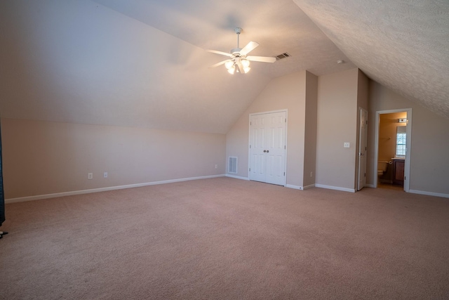 additional living space with baseboards, visible vents, ceiling fan, vaulted ceiling, and light carpet