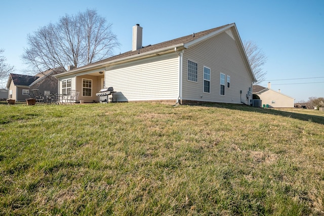 back of property with a lawn and a chimney