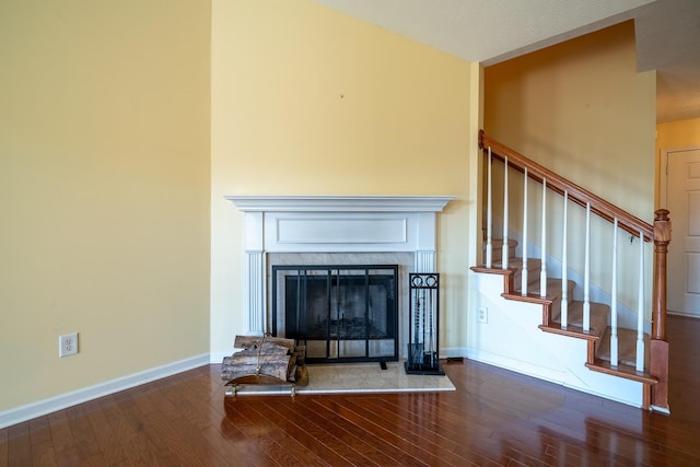 interior space with a fireplace with raised hearth, baseboards, and wood finished floors