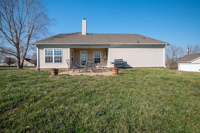 back of house with a yard, a patio area, roof with shingles, and a chimney