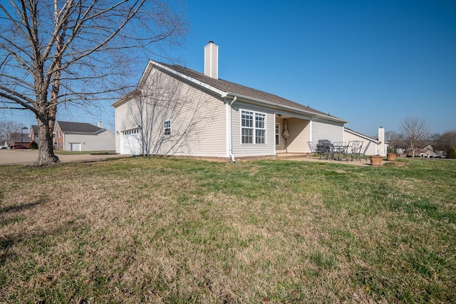 rear view of house with a patio, a chimney, and a yard