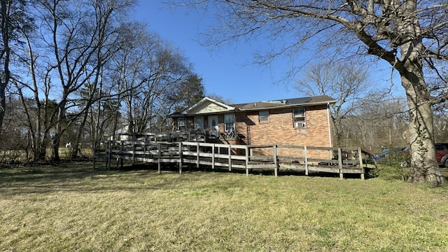 rear view of house with a lawn, brick siding, and a wooden deck