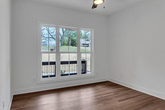 empty room with a ceiling fan, wood finished floors, and baseboards