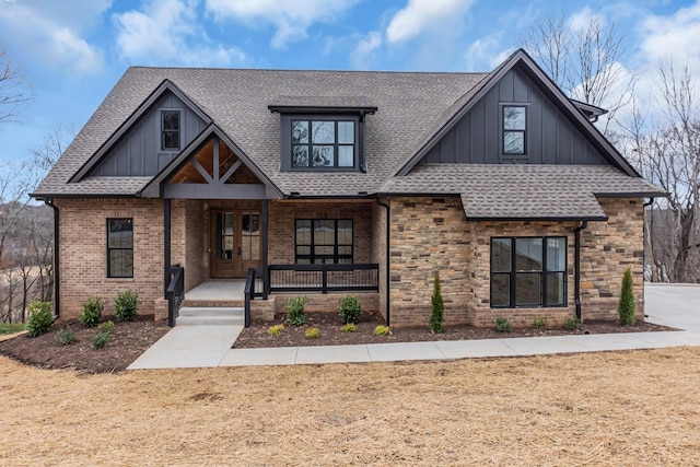 view of front of home featuring board and batten siding, covered porch, stone siding, and a shingled roof