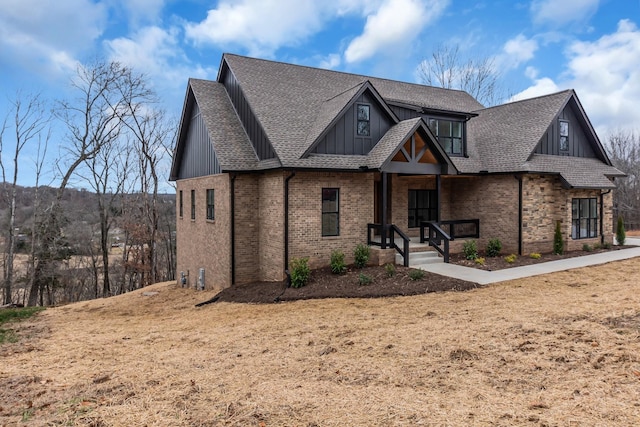 view of front of property featuring brick siding, board and batten siding, and roof with shingles