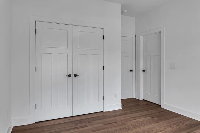 unfurnished bedroom with a closet, baseboards, and wood finished floors