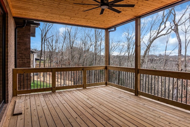 wooden terrace featuring a view of trees and ceiling fan