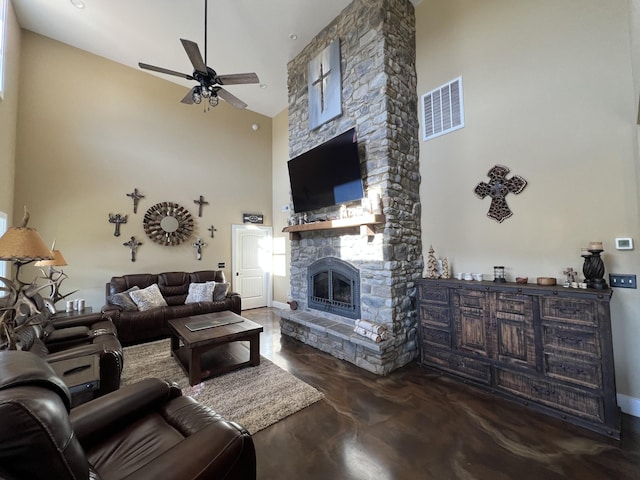 living area featuring finished concrete flooring, visible vents, a high ceiling, a fireplace, and ceiling fan