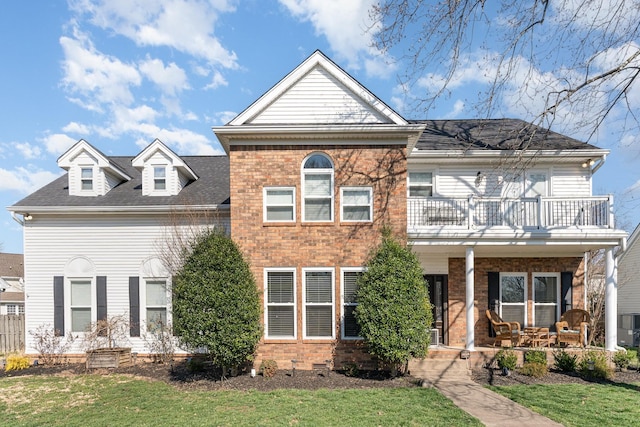 view of front of house with a balcony, covered porch, and brick siding