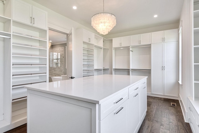 spacious closet with visible vents, an inviting chandelier, and dark wood-style floors