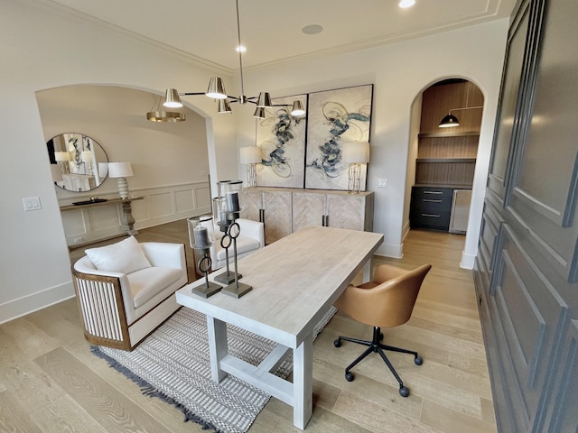 office with a wainscoted wall, arched walkways, crown molding, a decorative wall, and light wood-type flooring