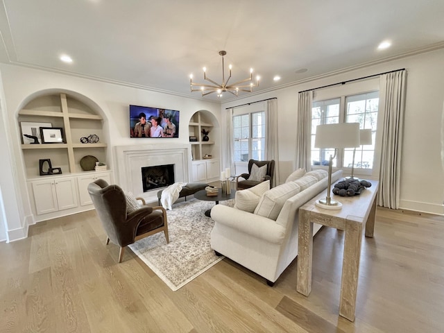 living area featuring crown molding, light wood-style flooring, and built in features