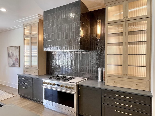 kitchen featuring tasteful backsplash, light wood finished floors, glass insert cabinets, baseboards, and range with two ovens