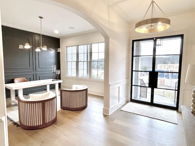 entryway featuring a wealth of natural light, arched walkways, ornamental molding, and a decorative wall