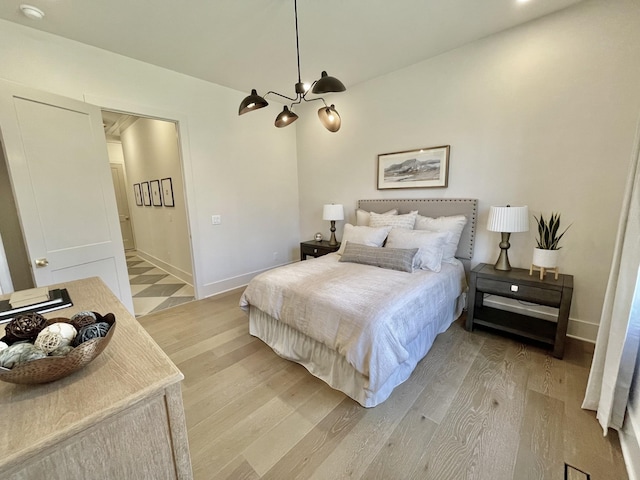 bedroom featuring a notable chandelier, light wood-style floors, and baseboards