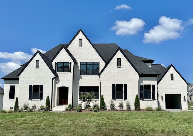 view of front of house with a front yard, a garage, and brick siding