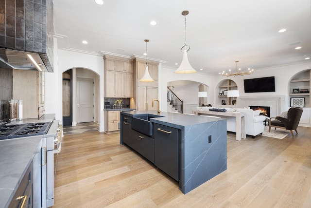 kitchen with light wood finished floors, recessed lighting, arched walkways, a sink, and crown molding