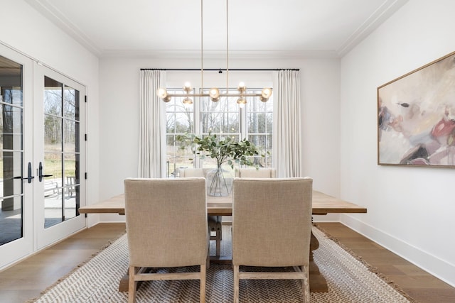 dining room with wood finished floors, baseboards, french doors, crown molding, and a notable chandelier