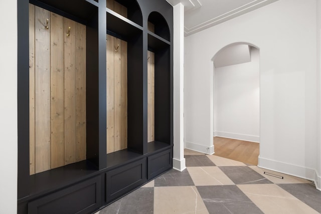 mudroom with arched walkways, tile patterned floors, and baseboards