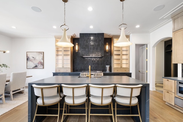 kitchen featuring dark countertops, ornamental molding, light wood-type flooring, and light brown cabinetry