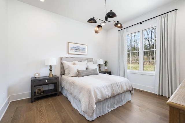 bedroom with a notable chandelier, wood finished floors, and baseboards