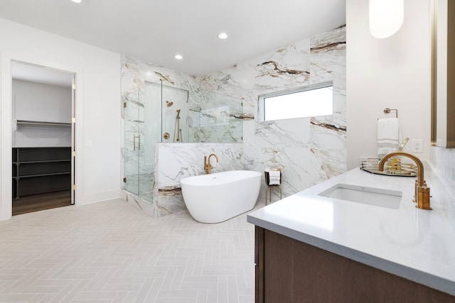 bathroom with a sink, recessed lighting, a marble finish shower, a soaking tub, and a spacious closet