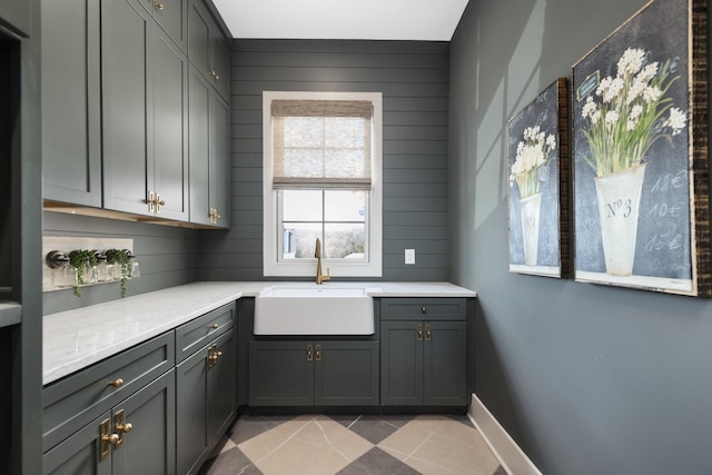 kitchen with baseboards, light countertops, light tile patterned floors, gray cabinets, and a sink