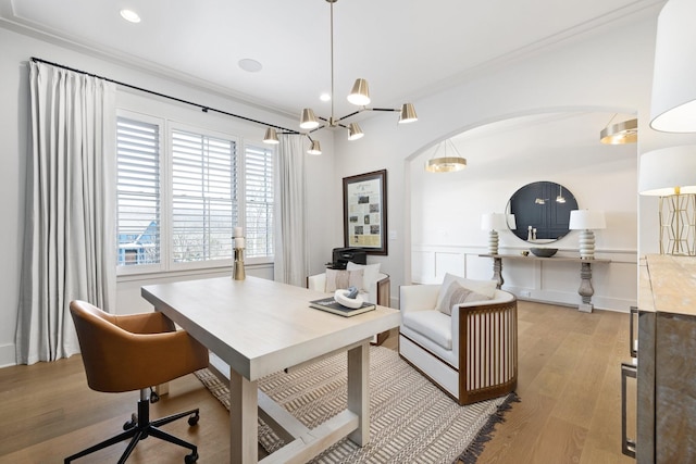 office with light wood-type flooring, arched walkways, wainscoting, a decorative wall, and crown molding