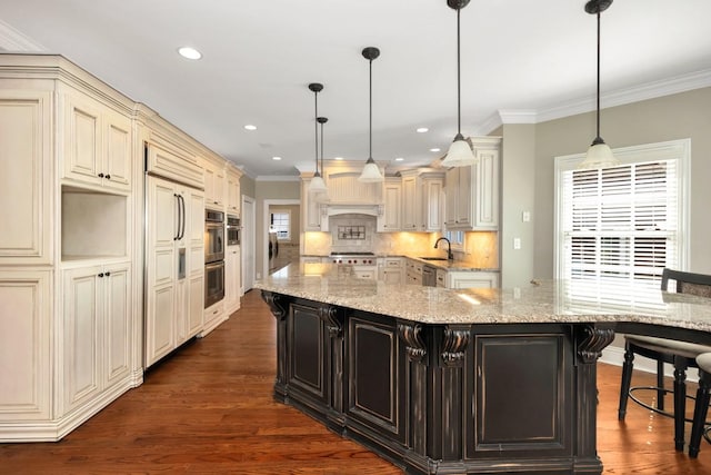 kitchen with dark wood finished floors, a sink, cream cabinetry, appliances with stainless steel finishes, and crown molding