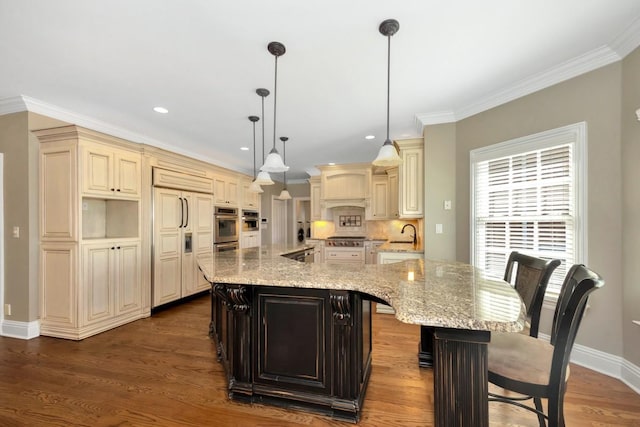 kitchen featuring a spacious island, crown molding, dark wood-type flooring, cream cabinetry, and stainless steel appliances