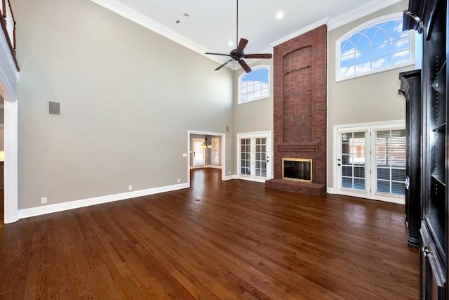 unfurnished living room with a brick fireplace, crown molding, a ceiling fan, and dark wood-style flooring