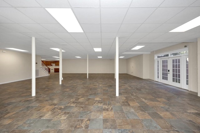 finished below grade area with stairs, stone finish floor, french doors, and a paneled ceiling