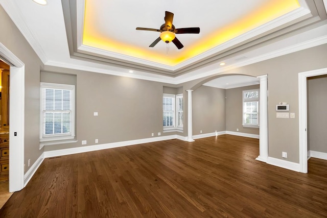 spare room with baseboards, a raised ceiling, dark wood-style flooring, and ornate columns