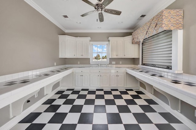 kitchen featuring visible vents, ornamental molding, dark floors, and white cabinetry