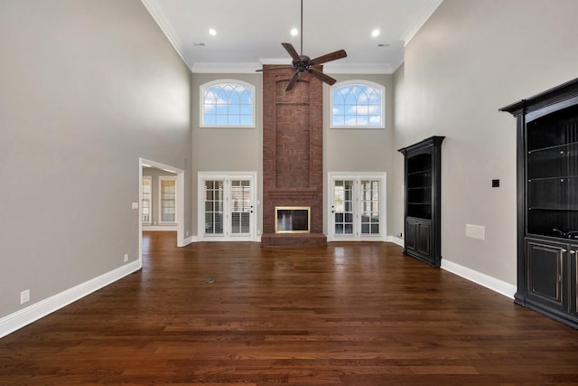 unfurnished living room featuring a healthy amount of sunlight, crown molding, baseboards, a fireplace, and dark wood-style floors