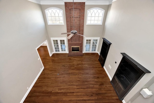 unfurnished living room featuring a brick fireplace, plenty of natural light, wood finished floors, and ceiling fan