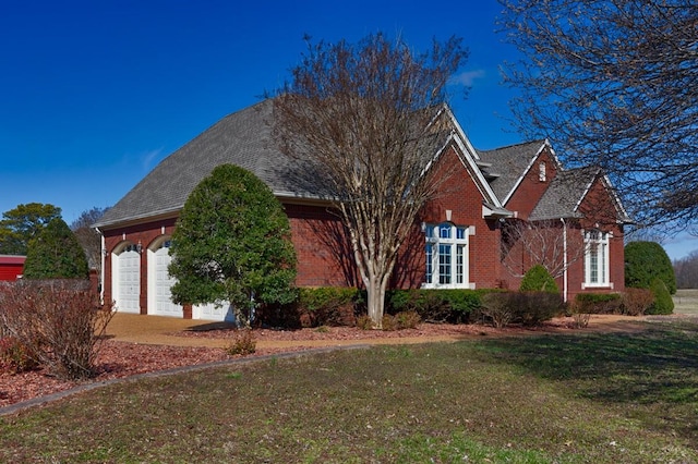 view of front of property with a front lawn, a garage, and brick siding