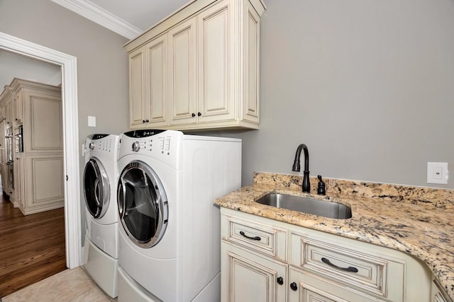 laundry room with washing machine and clothes dryer, crown molding, cabinet space, and a sink