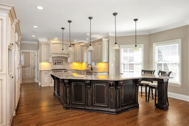 kitchen featuring a sink, decorative backsplash, a spacious island, and a breakfast bar area