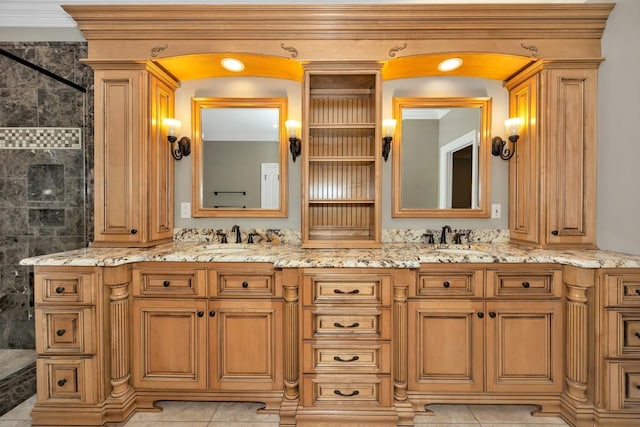 bathroom with double vanity, tiled shower, tile patterned floors, and a sink