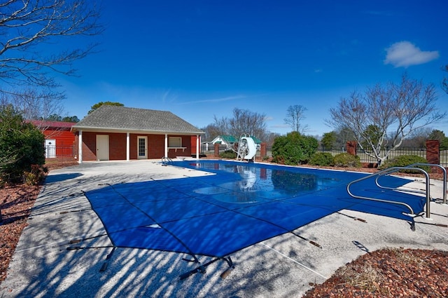 view of pool with an outbuilding, a storage structure, a patio, fence, and a water slide