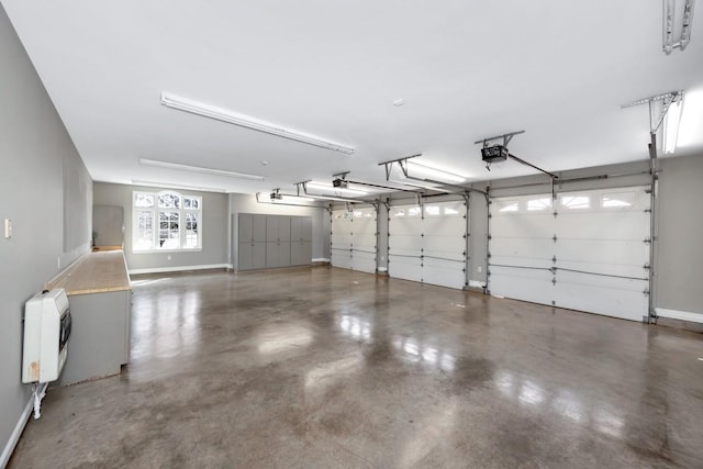 garage featuring heating unit, a garage door opener, and baseboards