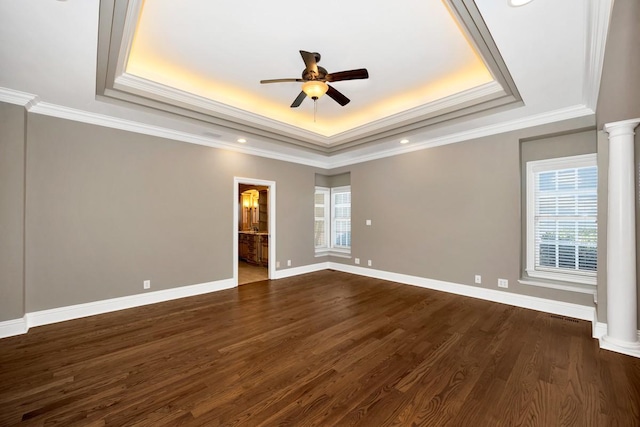 unfurnished room featuring a ceiling fan, baseboards, ornate columns, a tray ceiling, and dark wood-type flooring