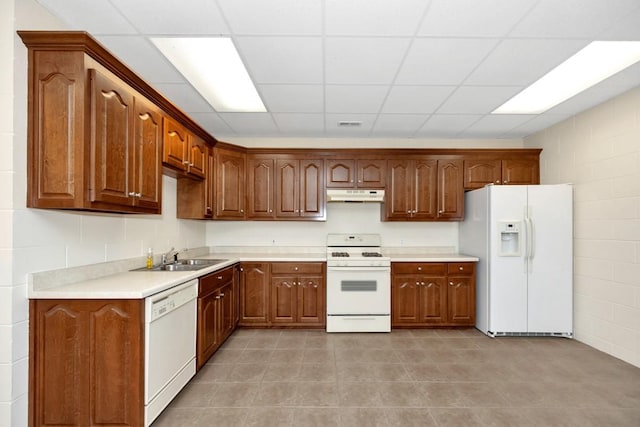 kitchen with under cabinet range hood, a sink, white appliances, light tile patterned flooring, and light countertops