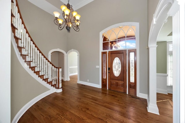 entryway with dark wood finished floors, a high ceiling, arched walkways, and a chandelier