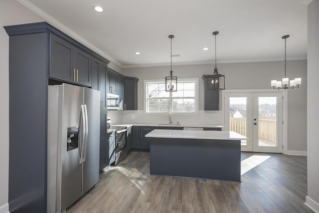 kitchen with a kitchen island, a sink, ornamental molding, light countertops, and stainless steel appliances