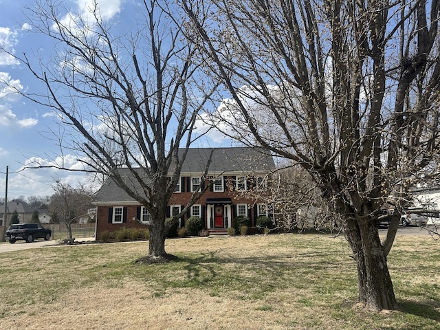 colonial home featuring a front yard and brick siding